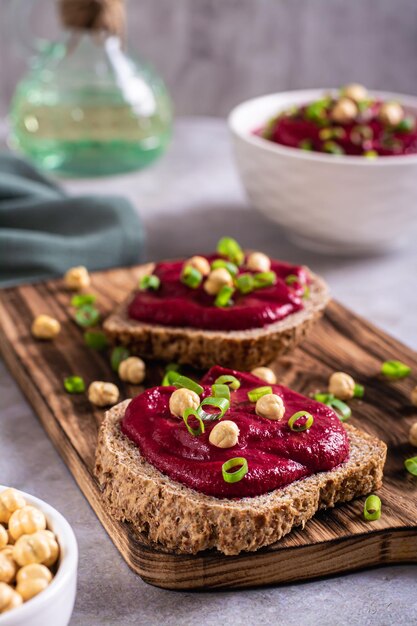 Zelfgemaakte roggebroodsandwiches met bietenhummus en kruiden op een snijplank verticaal zicht