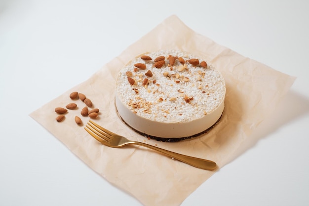 Zelfgemaakte ronde cake met noten op perkamentpapier eten bezorgen zelfgemaakt bakken bovenaanzicht heerlijke taart met noten en gouden vork op de witte tafel