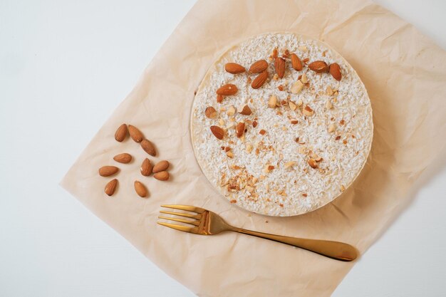 Zelfgemaakte ronde cake met noten op perkamentpapier Levering van maaltijden Zelfgemaakt bakken Bovenaanzicht Heerlijke taart met noten en gouden vork boven op de witte tafel