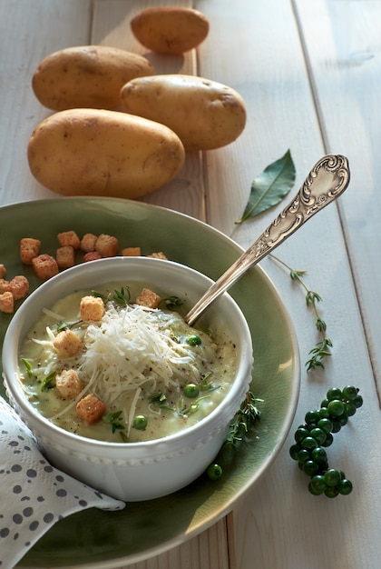 Zelfgemaakte room van aardappelsoep in mok met croutons, Parmezaanse kaas en tijm