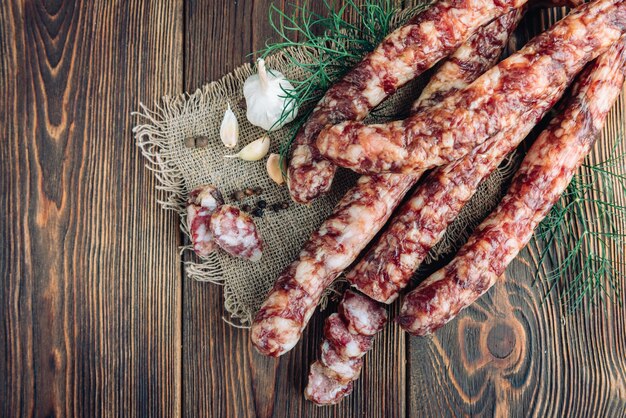 Zelfgemaakte salami gedroogde worstjes met peper, knoflook en dille op donkere houten tafel.