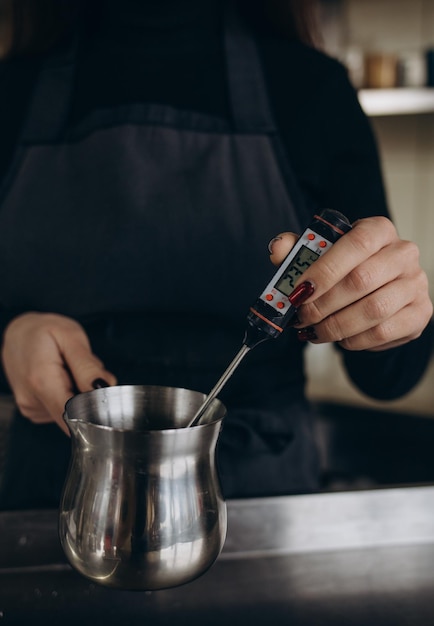 Zelfgemaakte sessie kaarsen maken met sojawas en diverse glazen bakjes Foto toont een paar handen die een thermometer gebruiken om de temperatuur van sojawas te controleren