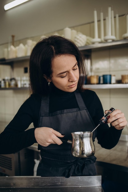 Zelfgemaakte sessie kaarsen maken met sojawas en diverse glazen bakjes Foto toont een paar handen die een thermometer gebruiken om de temperatuur van sojawas te controleren