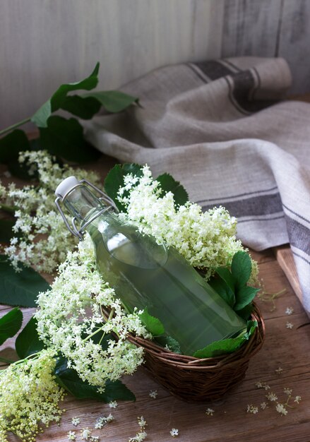 Zelfgemaakte siroop van vlierbessen bloemen in een glazen pot en vlier takken op een houten tafel Rustieke stijl.