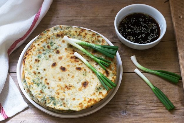 Foto zelfgemaakte smakelijk lente-uitjes pannenkoeken en een bos van groene uien. rustieke stijl.