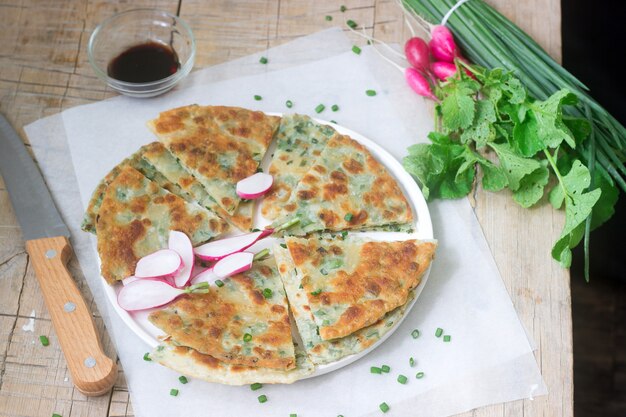 Zelfgemaakte smakelijk scallion pannenkoeken met een bos van groene uien en radijs