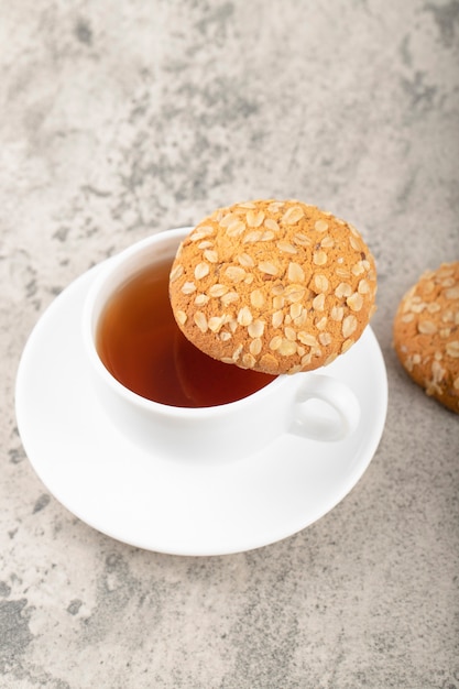 Zelfgemaakte smakelijke havermoutkoekjes met kopje thee op steen.