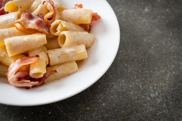 zelfgemaakte spaghetti rigatoni pasta met witte saus en spek - Italiaanse eetstijl