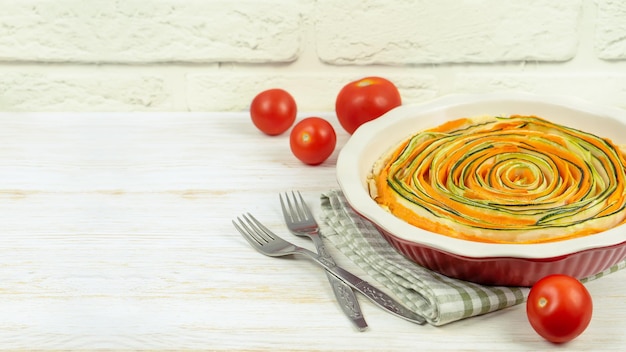 Zelfgemaakte spiraal groente taart taart van wortelen, courgette en aubergine op witte houten achtergrond