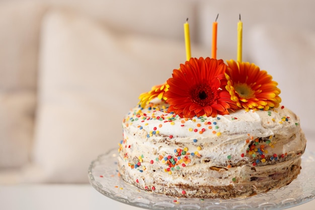 Zelfgemaakte taart gedecoreerd met veelkleurige bloemen en kaarsen