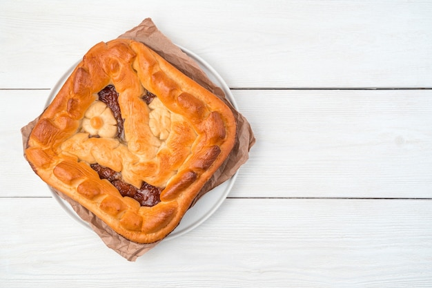 Zelfgemaakte taart met appelvulling op een vlakke plaat met kraftpapier op een lichte achtergrond.