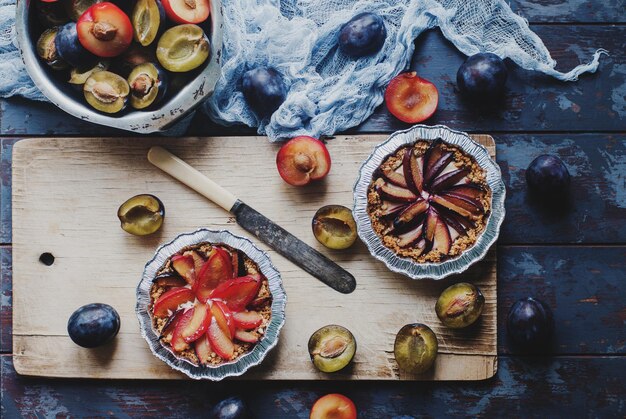 Zelfgemaakte taart van verse biologische pruimen op een houten bord en rustieke tafel Seizoensgebonden gezond vegetarisch eten herfst dessert bovenaanzicht selectieve aandacht