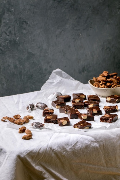 Zelfgemaakte toffee gezouten karamel chocolade amandel noten snoep op verfrommeld papier over wit linnen tafellaken. Handgemaakte voedsel zoete geschenken voor elke vakantie.