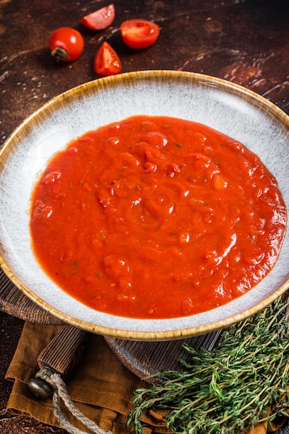 Zelfgemaakte tomaat Passata in rustieke plaat met kruiden Donkere achtergrond Bovenaanzicht