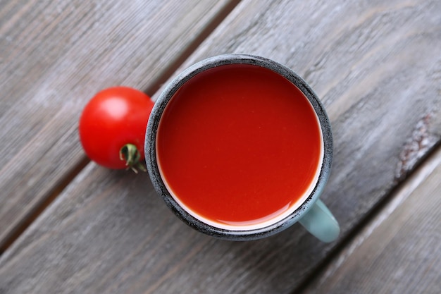 Zelfgemaakte tomatensap in kleur mok en verse tomaten op houten achtergrond