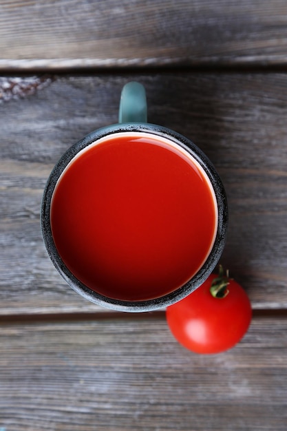Zelfgemaakte tomatensap in kleur mok en verse tomaten op houten achtergrond