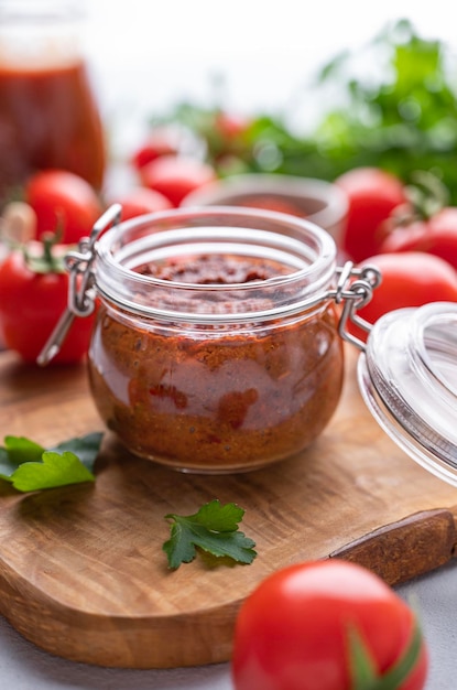 Zelfgemaakte tomatensaus voor pizza of pasta in een pot op een lichte achtergrond met verse groenten en kruiden close-up