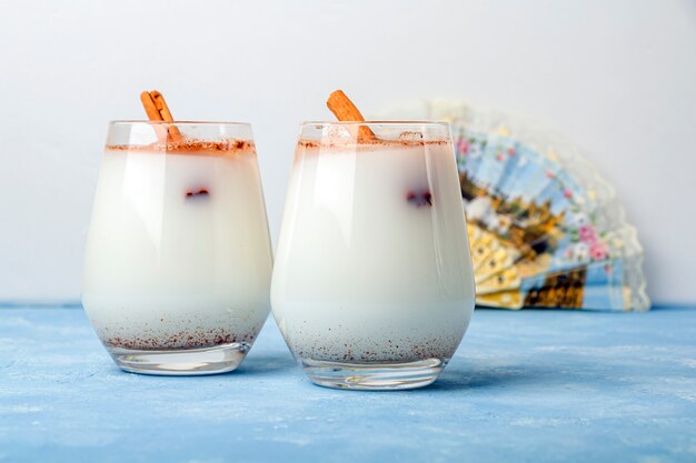 Zelfgemaakte traditionele Mexicaanse rijst Horchata in een glas en maracas op blauwe achtergrond. Fris koel drankje of cocktail gemaakt van rijst, vanille en kaneel of amandel. Cinco de Mayo achtergrond