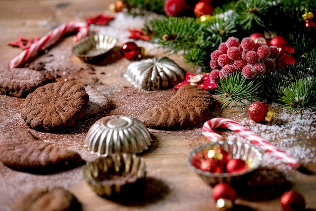 Zelfgemaakte traditionele zandkorst koekjes chocolade halve manen met cacaosuikerglazuur suiker in keramische plaat met koekjesvormen, spar, rode kerststerren decoraties over houten oppervlak.