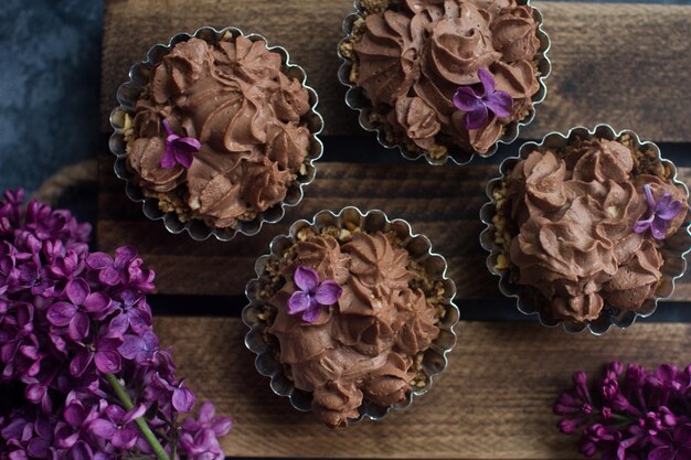 Zelfgemaakte vanille cupcake met chocolade glazuur op houten houten ondergrond met lila, bovenaanzicht. Heerlijk dessert voor verjaardag, feestdagen, verloving of valentijnsdag