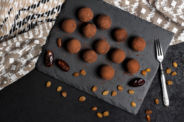 Foto zelfgemaakte vegan truffels met gedroogd fruit, walnoten en rauwe cacaopoeder geserveerd op zwarte leisteen plaat