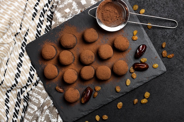 Zelfgemaakte veganistische truffels met gedroogd fruit, walnoten en rauw cacaopoeder geserveerd op zwarte leisteenplaat