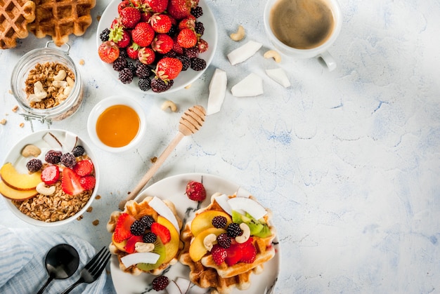 Zelfgemaakte verse Belgische zachte wafels met honing, vers fruit, noten en bessen