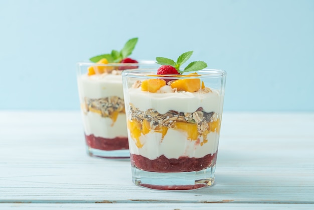 zelfgemaakte verse mango en verse framboos met yoghurt en granola - gezonde voeding