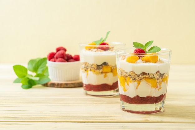 zelfgemaakte verse mango en verse framboos met yoghurt en granola - gezonde voeding