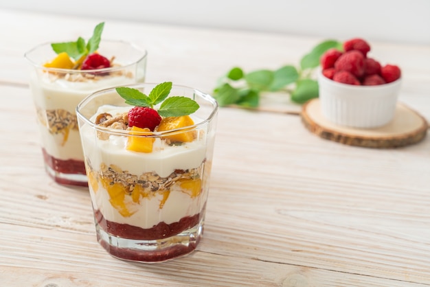 zelfgemaakte verse mango en verse framboos met yoghurt en granola - healthy food style