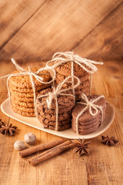 Zelfgemaakte volkoren koekjes met havermout, linnen en sesamzaadjes en traditionele koekjes met chocoladeschilfers op donkere rustieke houten tafel en kruiden.
