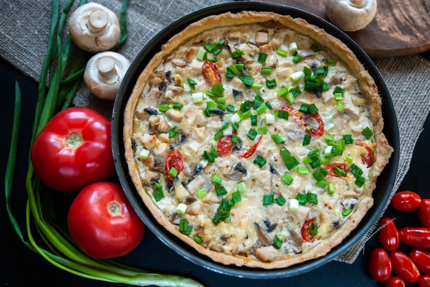 Zelfgemaakte warme quiche met ingrediënten tomaten en champignons stilleven plat thuis koken