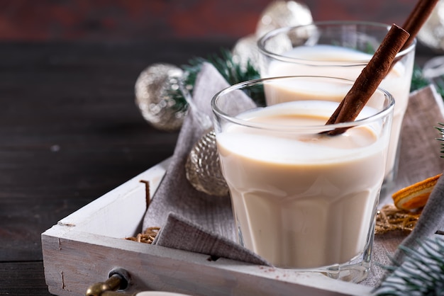 Zelfgemaakte White Holiday Eggnog met een kaneelstokje op donker. Kerst drankje