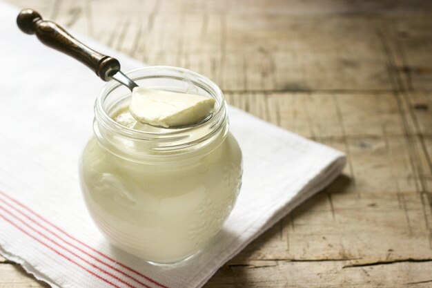 Zelfgemaakte yoghurt in een pot en lepel op een houten tafel. Rustieke stijl.