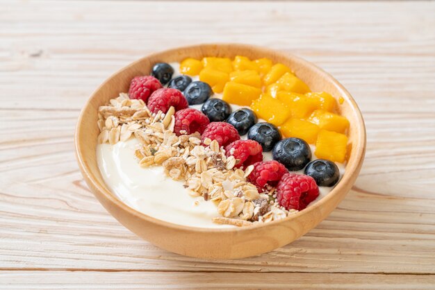 zelfgemaakte yoghurtkom met framboos, bosbes, mango en granola - gezonde voedingsstijl