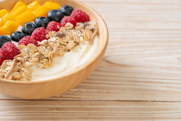 zelfgemaakte yoghurtkom met framboos, bosbes, mango en granola - gezonde voedingsstijl