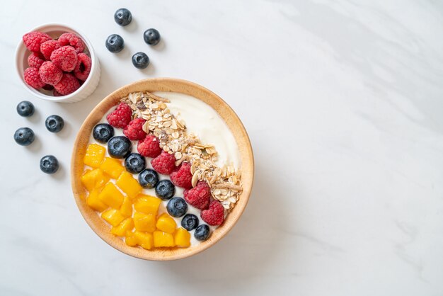 Zelfgemaakte yoghurtkom met framboos, bosbes, mango en granola - healthy food style