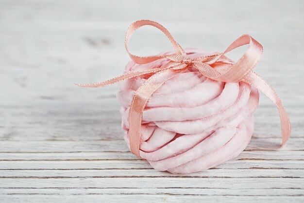 Zelfgemaakte zoete roze en witte marshmallow - zephyr op een lichte houten tafel.