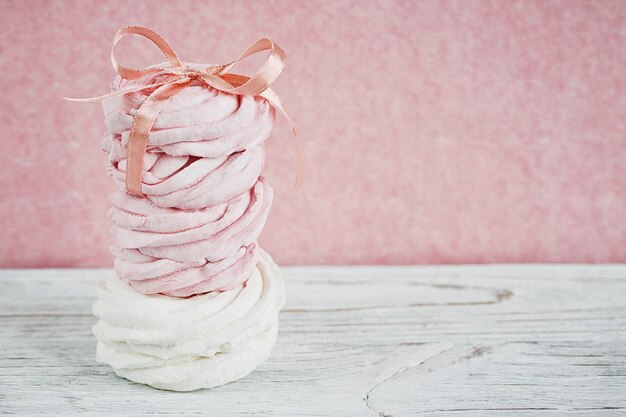 Zelfgemaakte zoete roze en witte marshmallow - zephyr op een lichte houten tafel.