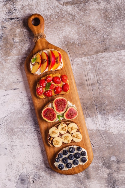 Zelfgemaakte zomertoast met roomkaas, notenboter en fruit en bessen bovenaanzicht