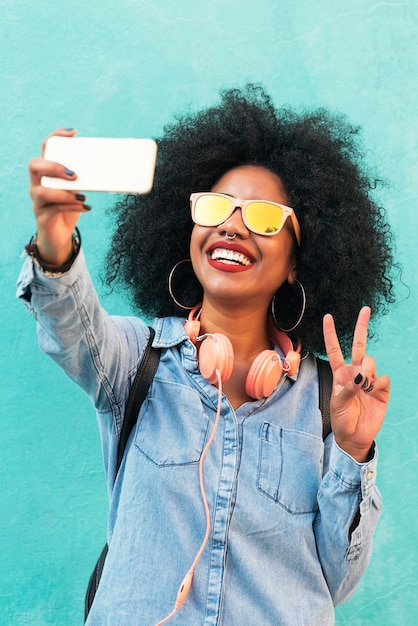 Zelfportret van mooie jonge afro-Amerikaanse vrouw die vredesteken maakt. Selfie-concept.