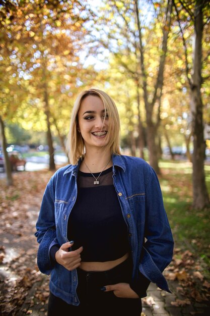 Zelfverzekerd blond aantrekkelijk glimlachend meisje in de natuur dat naar de camera kijkt