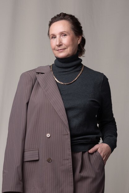 Zelfverzekerd en mooie blanke vrouw van oudere leeftijd poseren in een stijlvol pak in de fotostudio.