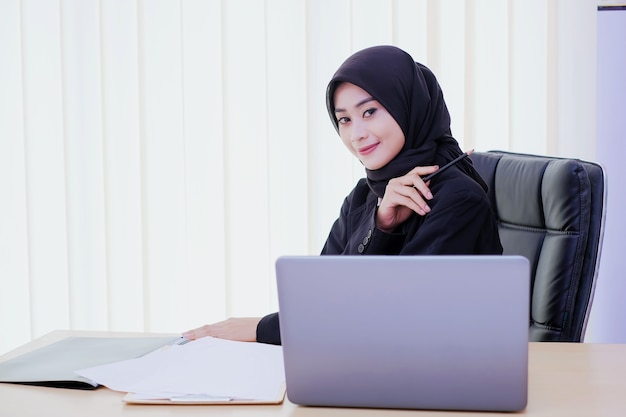 Zelfverzekerd gelukkig jonge zakenvrouw zittend aan een bureau op kantoor