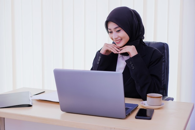 Zelfverzekerd gelukkig jonge zakenvrouw zittend aan een bureau