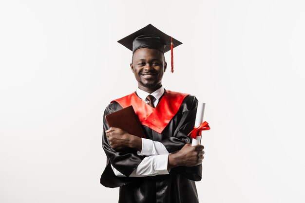 Zelfverzekerde afrikaanse student met diploma in afstudeergewaad en pet klaar om college af te ronden Toekomstige leider van de wetenschap Academicus afrikaanse man in zwarte toga glimlachend