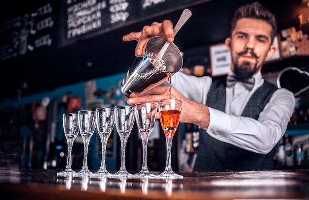 Foto zelfverzekerde barman maakt een show en creëert een cocktail in de nachtclub