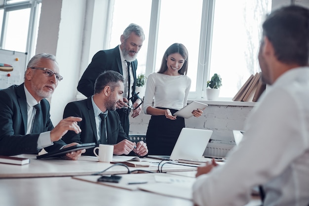 Zelfverzekerde collega's die bedrijfsuitbreiding bespreken terwijl ze samenwerken in het moderne kantoor