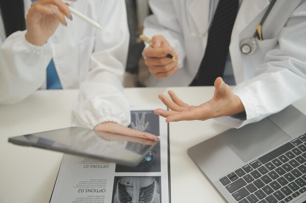 Zelfverzekerde dokter die een pillenfles vasthoudt en schrijft terwijl hij met een oudere patiënt praat en zijn medicatie in de kantoorruimte bekijkt