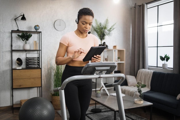 Foto zelfverzekerde gespierde sportieve zakenvrouw in hoofdtelefoon die op afstand van huis werkt met behulp van digitale tablet